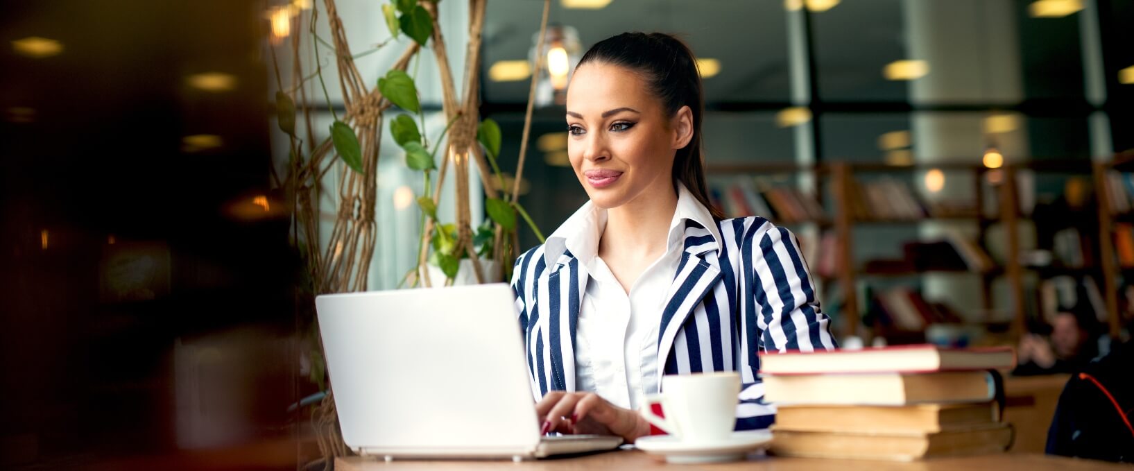 woman in striped business jacket sitting in library on computer
