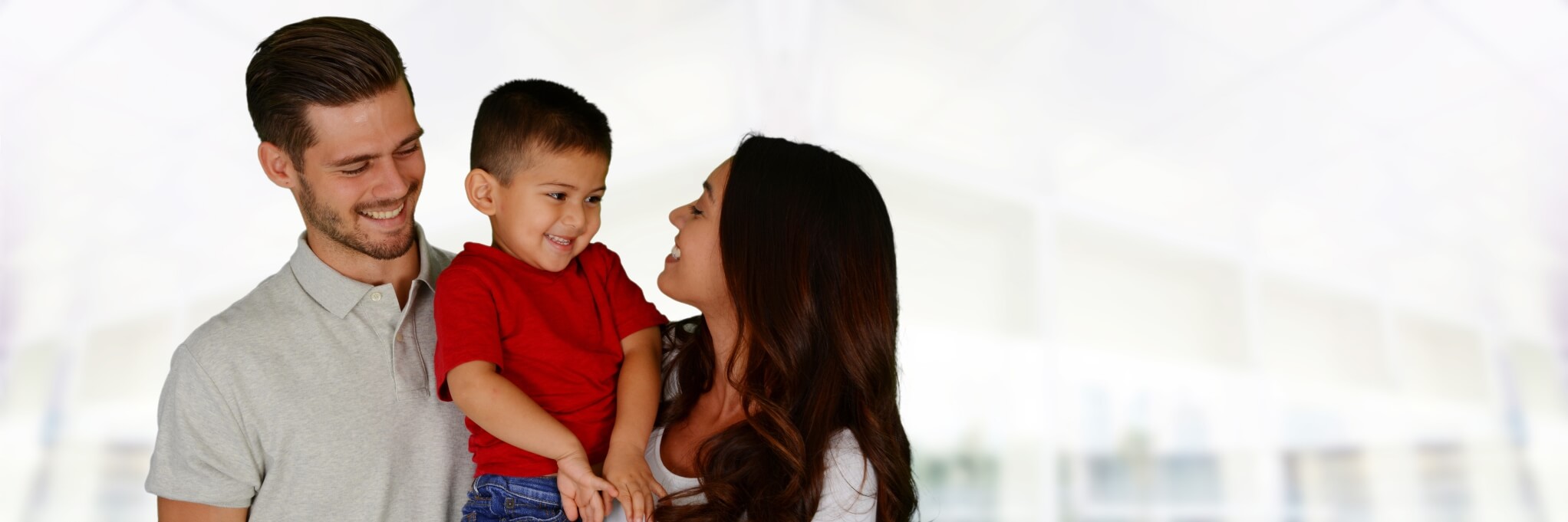 mother and father holding son and smiling at him