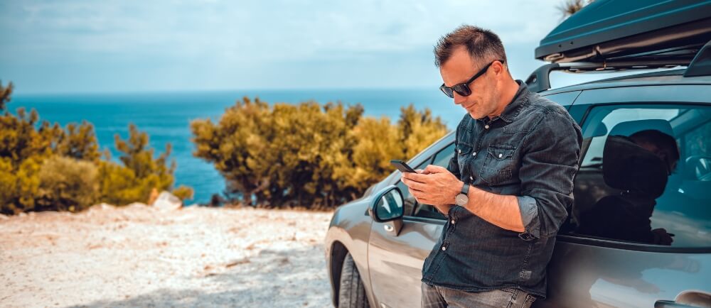 Man standing against car using Delta Dental mobile app