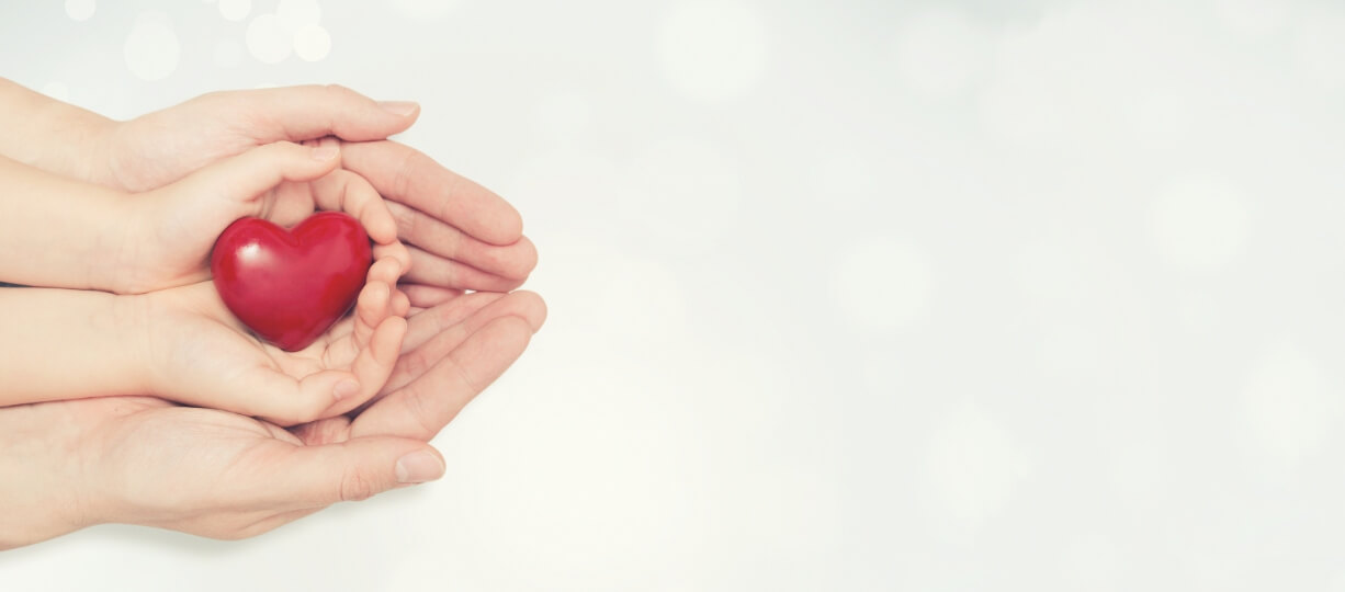 adult and child hands holding small red heart